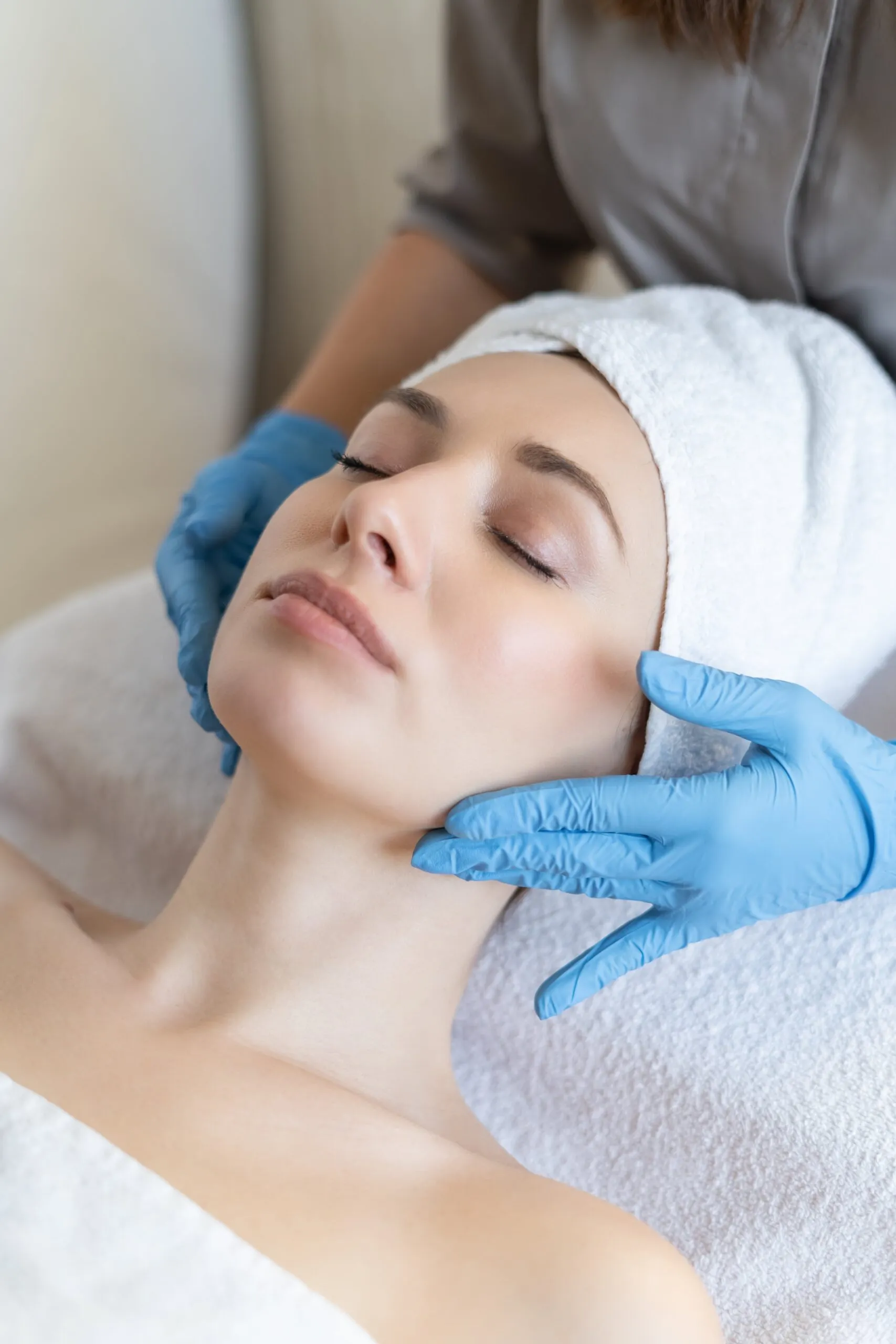 young-beautiful-girl-lies-table-beautician-receives-procedures-light-massage-hands-blue-gloves-skin-is-smooth-min-scaled